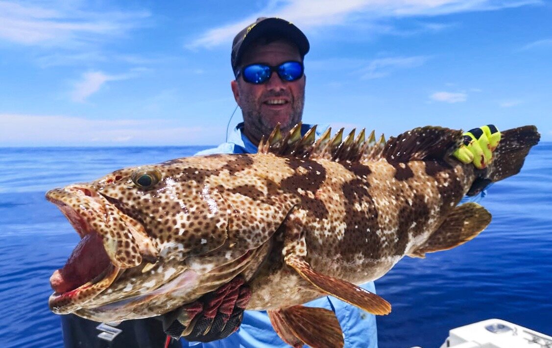 An angler holding a large grouper off Nosy Be