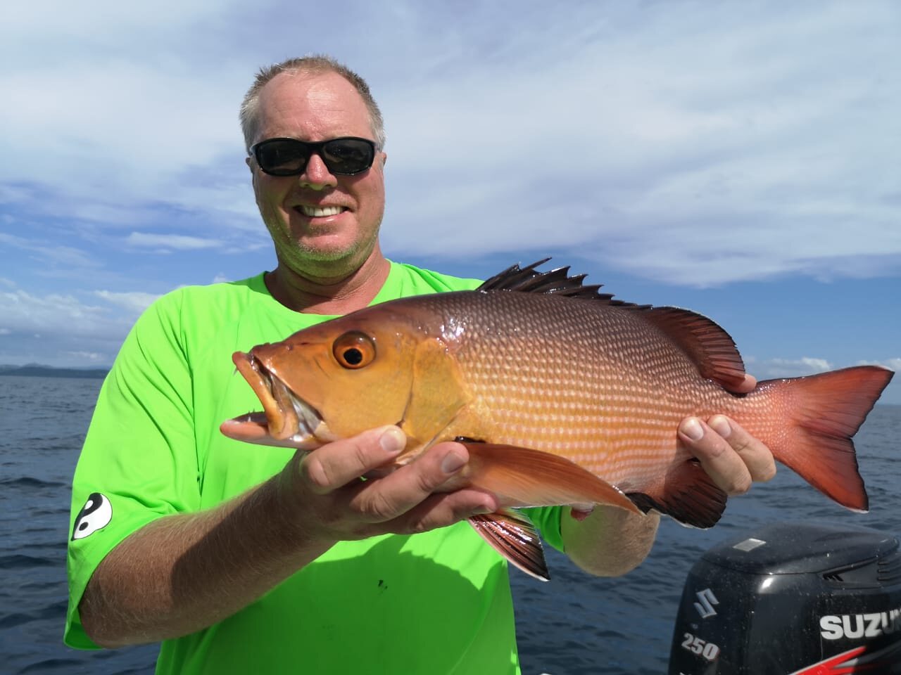 An angler holding a snapper at sea off Nosy Be