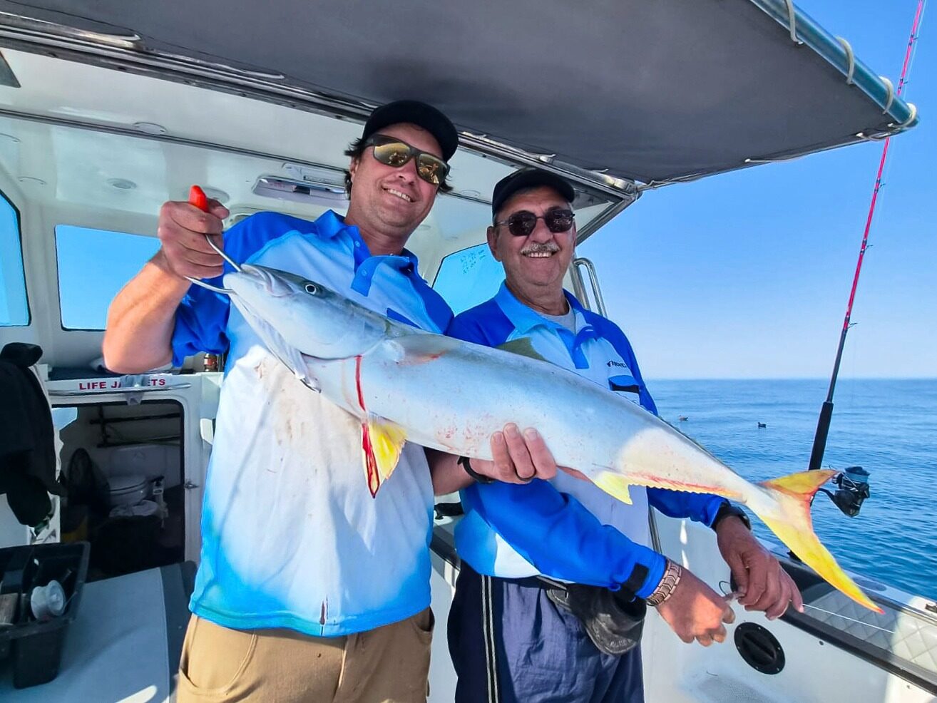 An amberjack, two anglers to hold it