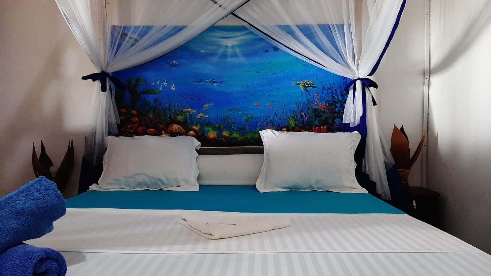 A bedroom with an ocean mural and mosquito net