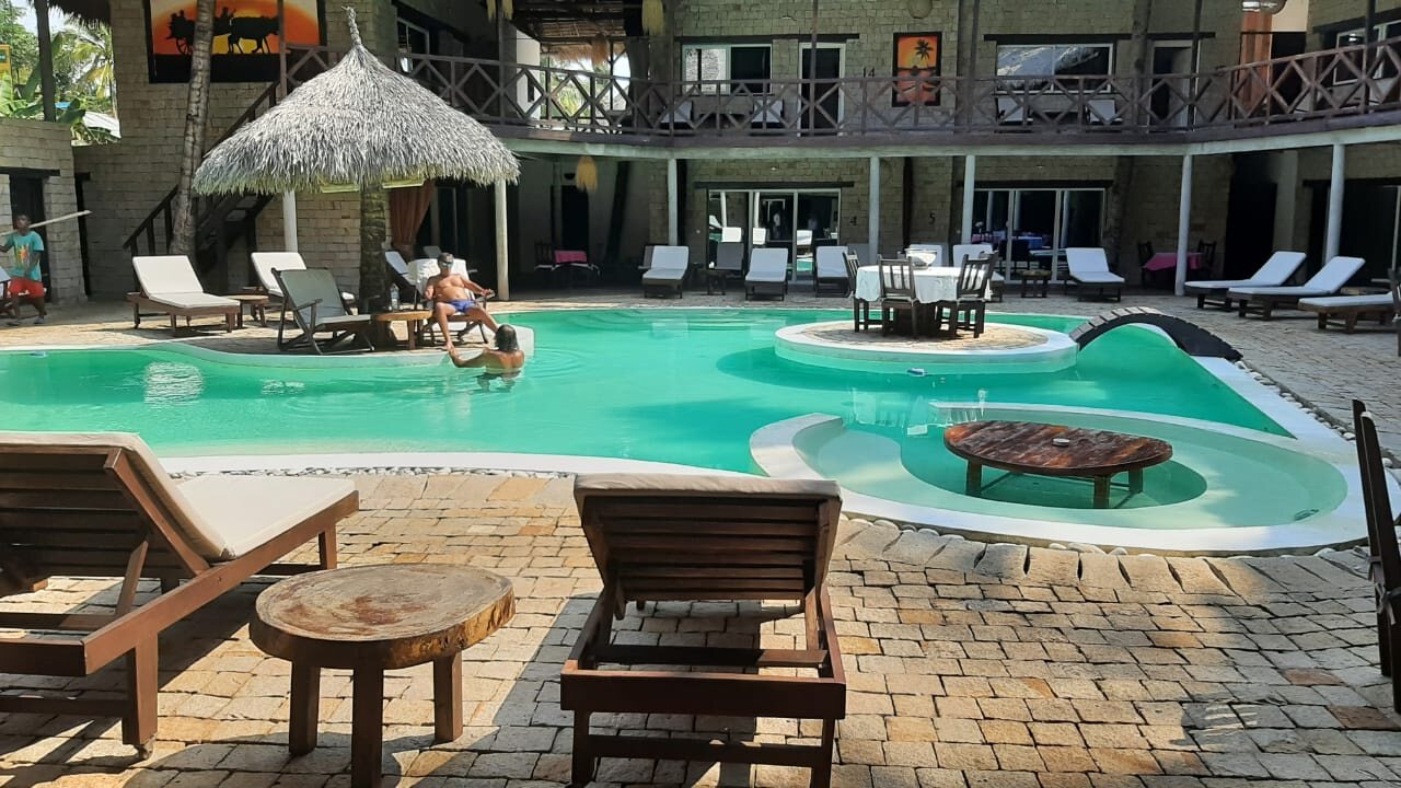 A resort pool with thatched umbrellas