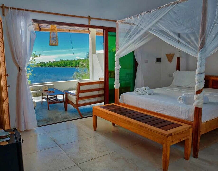A four-poster room opening onto the sea