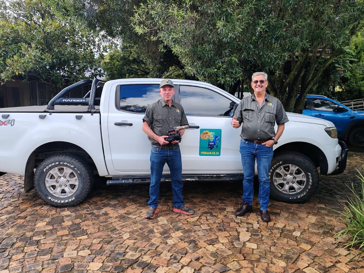 Two men beside a white bakkie with the Epic Paradise Tours logo on its door