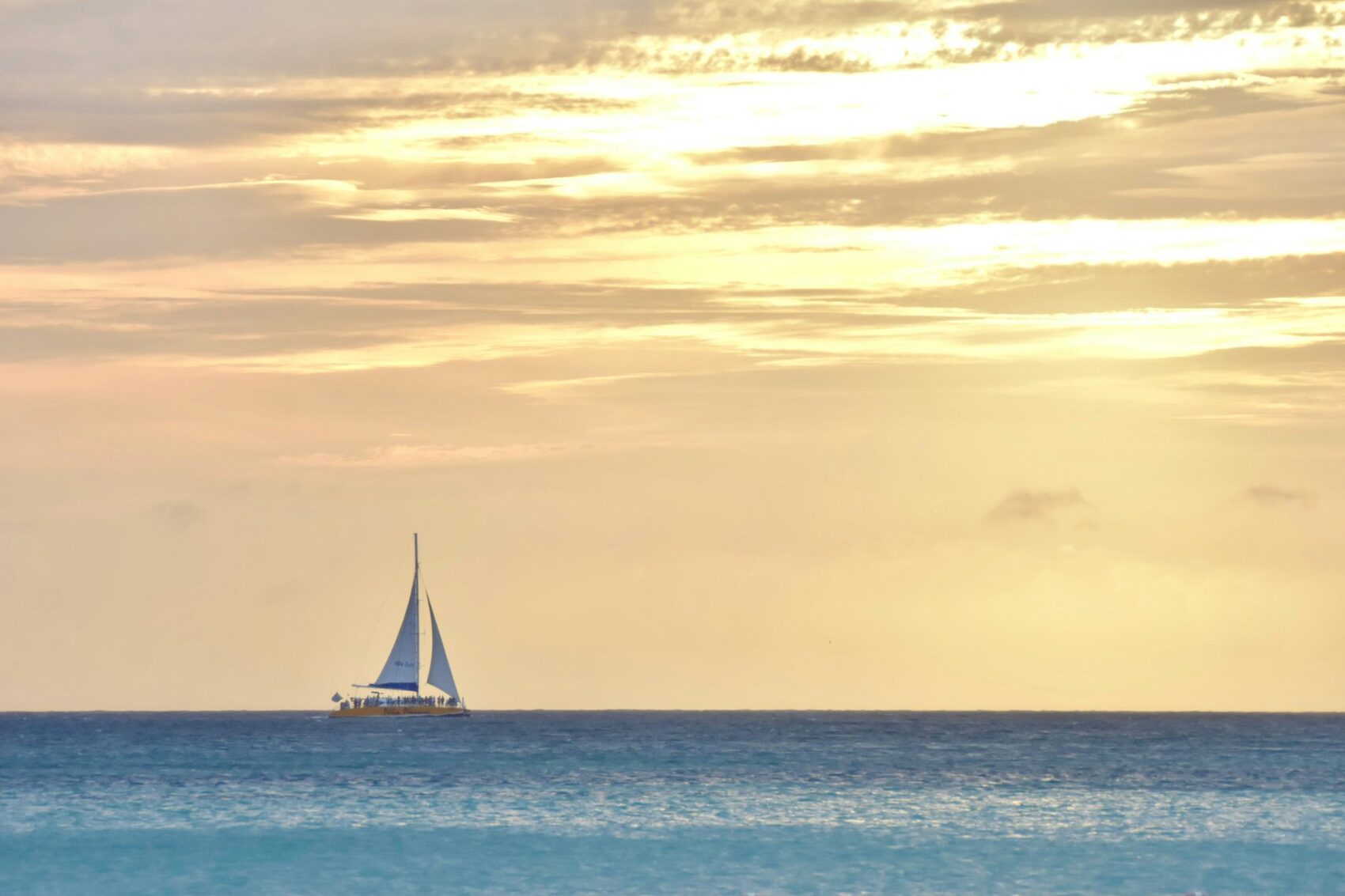 A sailing boat on calm water beneath a sunset sky