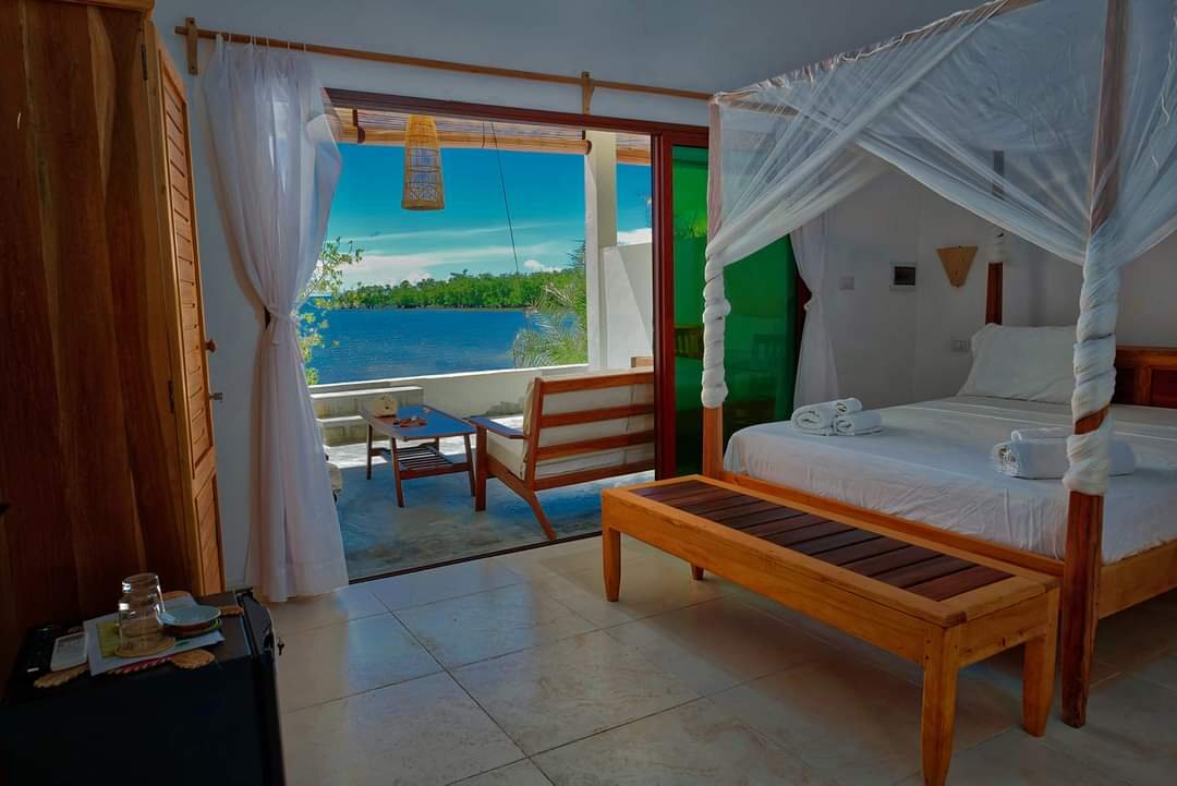 A bedroom with a canopy bed looking out to the sea on Nosy Be