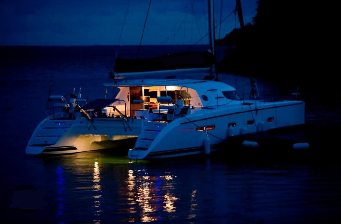 The liveaboard catamaran lit up at anchor at night