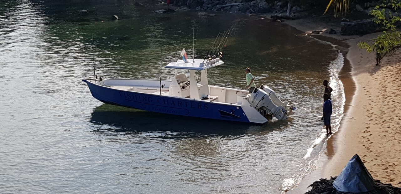 A centre-console fishing boat moored off a Nosy Be beach