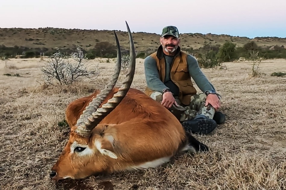 A hunter with an antelope trophy at sunset in the South African bushveld