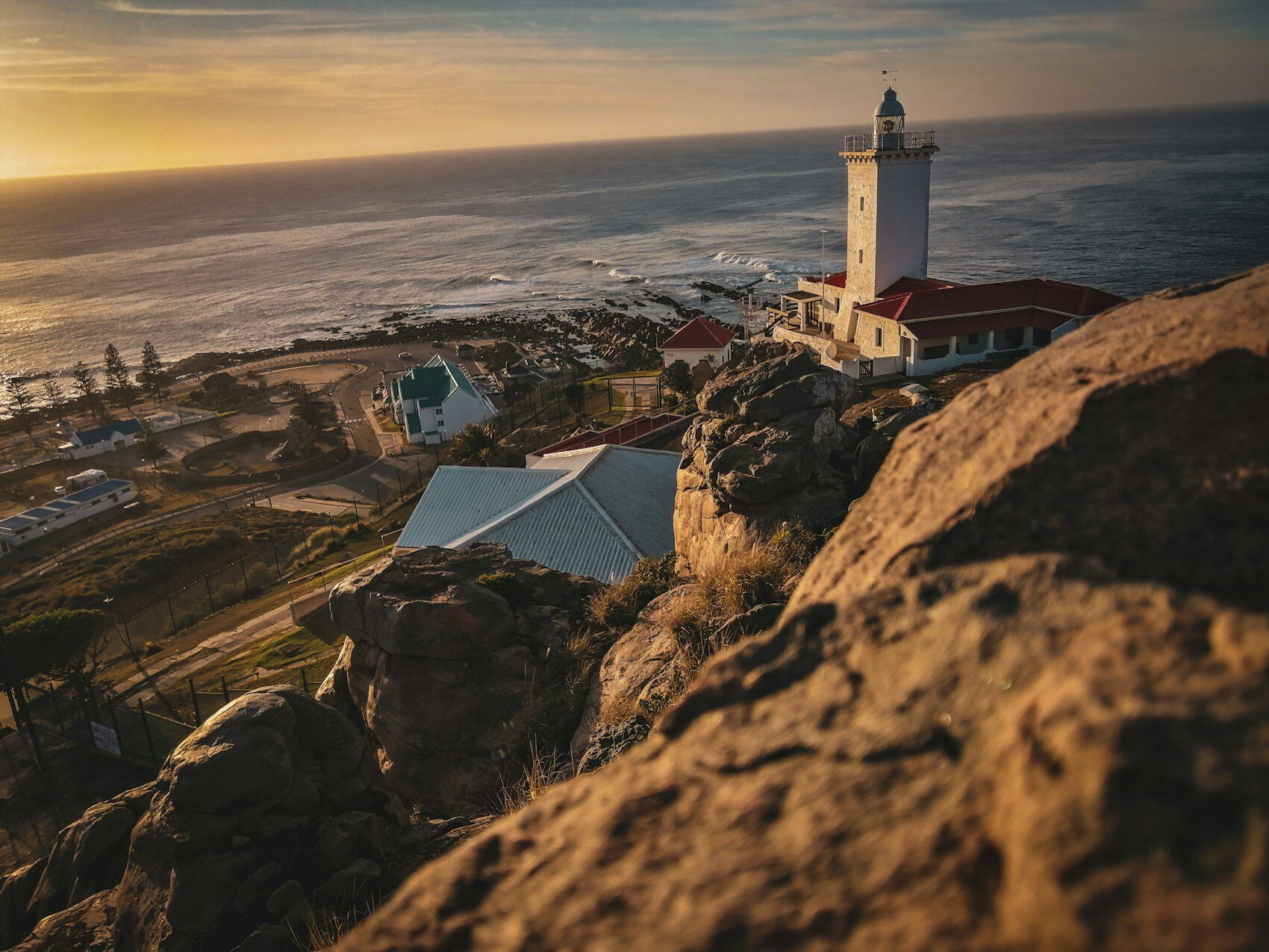 A lighthouse above the rocky South African coastline at sunrise