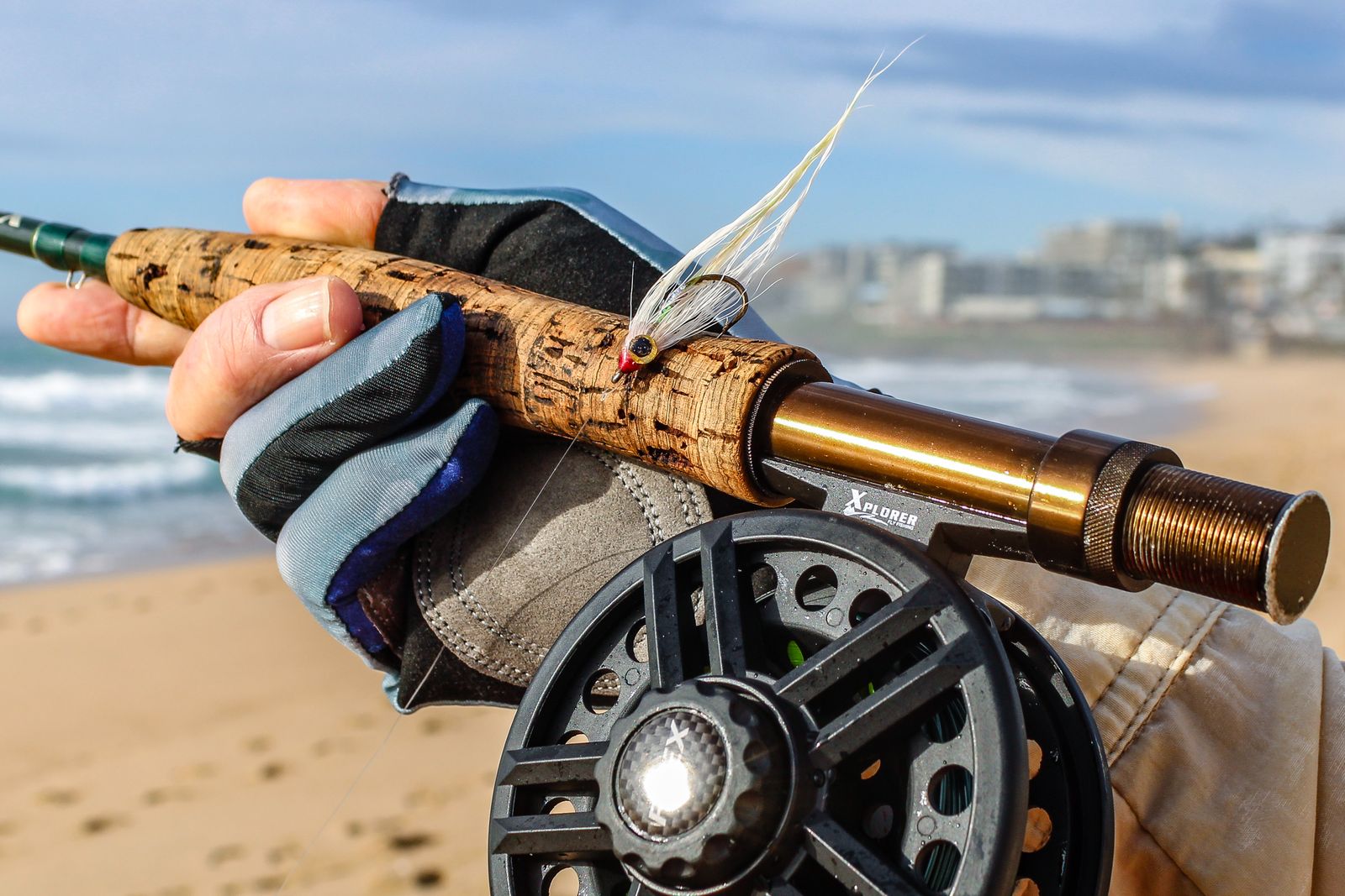 A fly rod and reel held on a beach