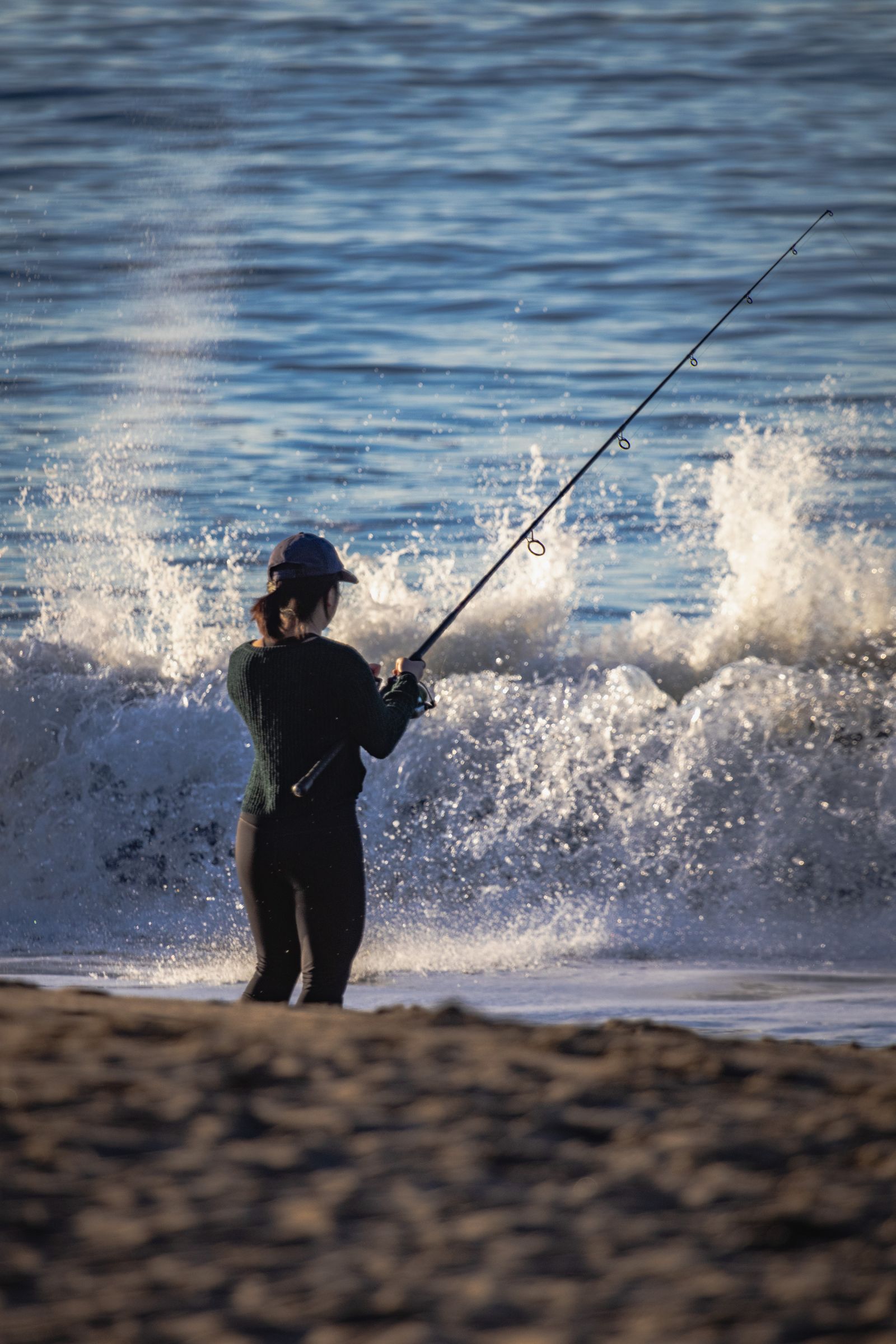 An angler casting into breaking surf